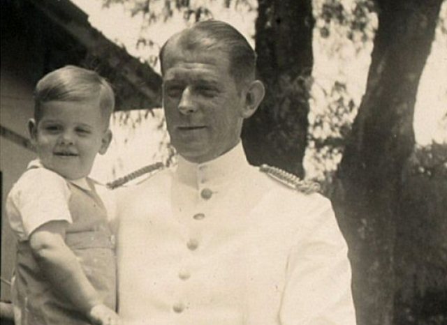 Man in marinekostuum met kind op arm